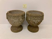 Front view of the two concrete planters side by side showing Greek key pattern and grapevine design