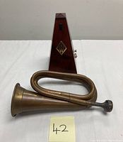 Frank Holton style brass bugle and wooden metronome side by side