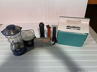 Photo showing camping items including a lantern, four flashlights, a fishing tackle box, and a MiniMate cooler.