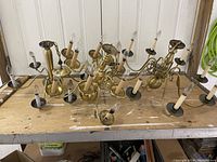 Three bronze finish chandeliers arranged on a wooden surface, showing multiple curved arms and candle bulb holders.