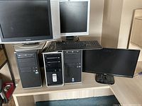 Photo showing three desktop computers, three computer monitors (one CRT SyncMaster), and one keyboard arranged on a wooden desk.