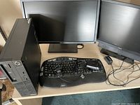 Dual Dell monitors, Lenovo desktop tower, Logitech ergonomic keyboard, wired mouse on table