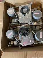 Open box showing the metal housings for pot lights with wiring and mounting brackets inside.