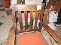 Front view of the oak rocking chair showing the vertical slat back and faux leather seat with tack details.