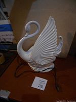 Side view of the white ceramic swan table lamp showing wing details and overall form with cord attached.