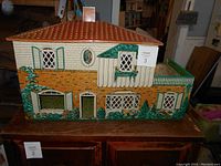 Front exterior view showing lithographed brick facade with windows, door, green shutters, balcony, and tiled roof.