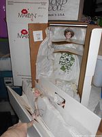 Marilyn Monroe and Diana bisque porcelain dolls in original packaging, showing details of gowns and original boxes.