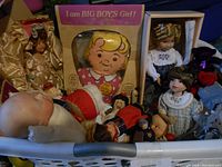 View of large laundry basket packed with multiple vintage dolls including boxed and loose, showing various types and styles from mid-20th century.