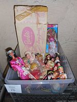 Boxlot of vintage Barbie dolls, a vintage Barbie bed box, and many All Nations vinyl dolls visible inside a plastic container.