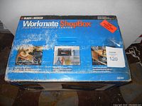Box showing Black & Decker branding, product name Workmate ShopBox, portable project center, model S8200, with printed images and product details, some wear on box.