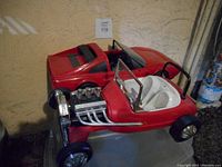 Photo showing the red vintage Barbie convertible car with chrome engine detail and the red coupe car side by side.