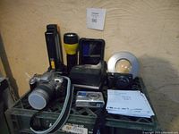 Photo of vintage camera lot showing multiple cameras including 35mm and digital models, lighting accessories, camera cases, and paperwork.