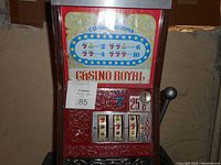 Front view of the red and silver Casino Royal vintage slot machine showing three reels, lever, and payout combination chart.