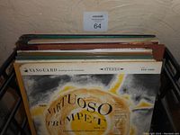 Metal rack holding a stack of vintage LP records, top record 'The Virtuoso Trumpet Vol. II' by Vanguard Records