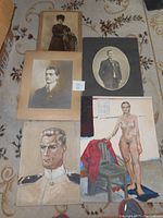 Top view of five vintage artworks including three black and white photographs, one nude oil painting, and one WWII Navy officer oil portrait, all displayed on a floor with patterned carpet.