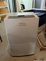 Front and side view of white NOMA dehumidifier showing brand label and unit shape.