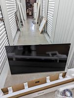 Front view of Vizio 55" flatscreen television leaning against a storage unit, showing screen and packaging foam