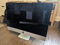 Front view of silver aluminum iMac on hardwood floor showing overall condition