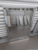Front view of a large rectangular bathroom mirror with beveled mirrored edges, standing upright leaning against a wall.