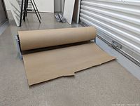 Paper roll dispenser and cutter with kraft paper roll showing partially dispensed paper.