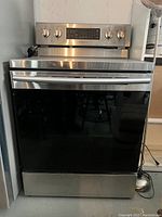 Front view of stainless steel electric range with smooth glass cooktop and control panel