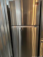 Full front view of stainless steel refrigerator showing top freezer and bottom fridge doors with integrated handles.