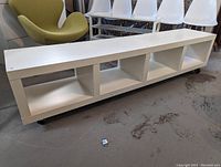 Front and side view showing the white storage unit with four open compartments and caster wheels
