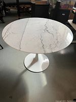 Angled full view of marble tabletop and white pedestal base