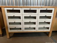 Front view of the work table showing the wooden frame, 12 labeled drawers with frosted glass panels, and metal knob handles.