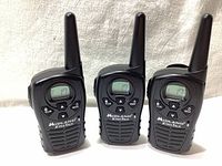 Photo showing three Midland LXT118 walkie talkies standing upright with LCD screens displaying channels 7, 10, and 17 respectively.