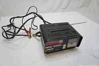 Front and side view of the Motomaster 6 amp battery charger showing control switch, meter and charging cables with alligator clips.