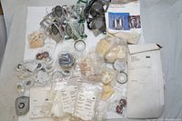 Top down view of assorted 3M dust masks, respirator facepieces, filters and accessories spread on white background showing a variety of items including filter cartridges and packaged parts.