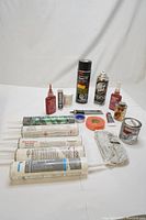 Photo of various adhesive sealants and insulating products laid out showing tubes, spray cans, small bottles, tape, and a can.