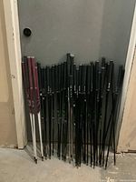 Photo showing a large mix of black and maroon golf shafts leaning against a wall, mostly with PING grips and visible branding for Prodi G and ULT240 Lite shafts.
