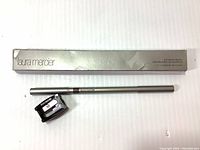 Full view of the Laura Mercier packaging box, the eyebrow pencil and sharpener laid out.