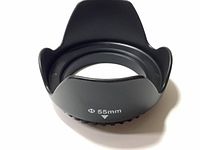 Front view of black plastic tulip-shaped camera lens hood marked 55mm diameter.