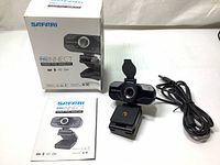 Front view of Safari Pro Connect 1080p FHD webcam showing camera lens, clip base, USB cable, user manual and retail box.