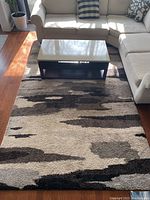 Full view of the thick pile area rug under a coffee table with sofas around it, showing its overall pattern and size in a room setting.