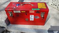 Red Beach metal tool box front view with closed lid and latches showing wear and stickers