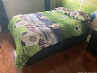 Full view of the double bed with soccer-themed bedding, showing mattress on frame.