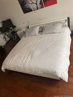 Full view of assembled platform bed in room showing white bedding and black and white upholstered frame.