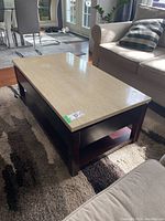 Coffee table with light beige laminated top and dark wood frame, shown from angled top view.