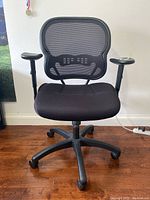 Front view of the black mesh back desk chair showing seat, armrests, and caster wheels.
