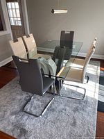 Overview of glass dining table with six vinyl chairs arranged around it