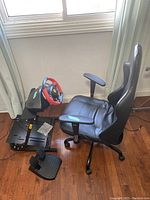 Gaming steering wheel mounted on metal wheel stand with pedal set and gaming chair beside it