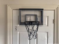 Front view of Franklin Pro Hoops indoor basketball hoop hanging on a door, showing transparent backboard and black rim with net.