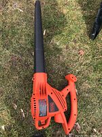 Top view of the Black and Decker electric leaf blower showing orange body and black nozzle on grass.
