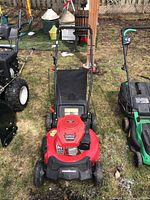 Front view of the red Powersmart lawn mower showing the Briggs & Stratton engine and black grass catcher bag.