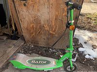 Side view of the full green Razor E200 electric scooter showing the deck, handlebar, and front wheel.
