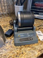 Front and top view of gray National Geographic branded hobby rock tumbler showing numbered settings and power buttons.